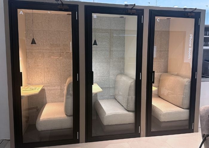 Three soundproofed phone booths at MSpace, each with a cushioned seat and fold-down desk